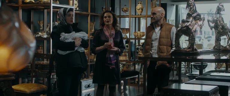 Can Evrenol'un yönettiği Cam Sehpa filminden Alper Kul, Hatice Aslan, Algı Eke'nin yer aldığı, cam sehpanın satılmak üzere olduğu sahne. Antika eşyalar gözüküyor.