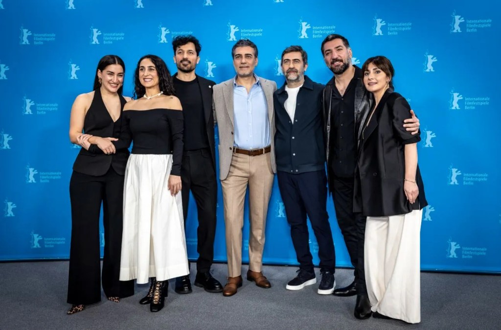 Kurtuluş film ekibi Berlinale'de film ekibi ile fotoğraf çekilmiş karede Berkay Ateş, yönetmen Emin Alper yer alıyor.