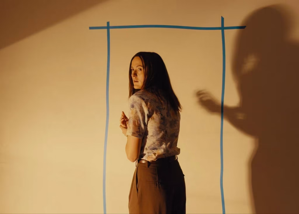 Mary Renata Reinsve backrooms filminde odada çizimlerin ortasında gerilim dolu görsel