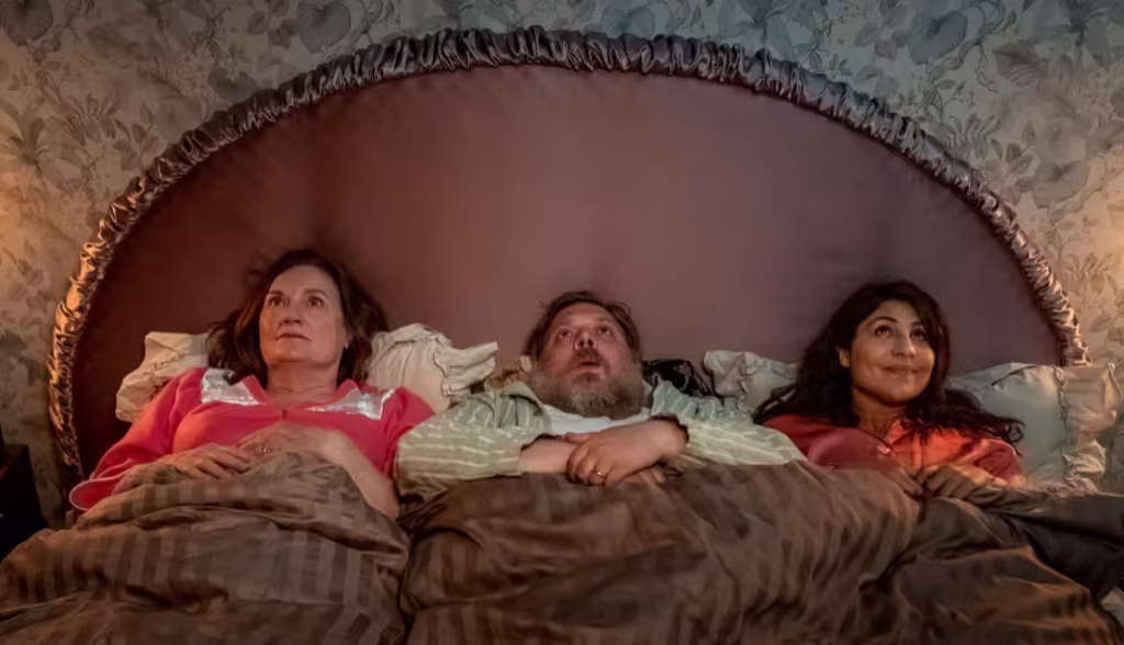 The Cake Dynasty (2022) filminde aynı yatakta uzanan üç karakter.