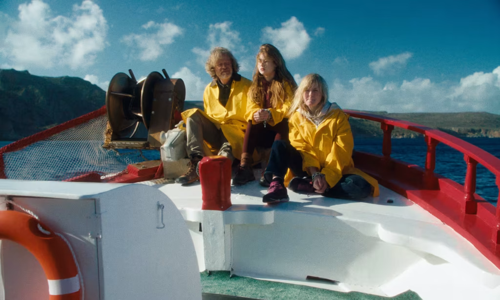Pirateland (2025) kısa filminde gemide giden turistler güverterde yağmurluklarla oturuyor.