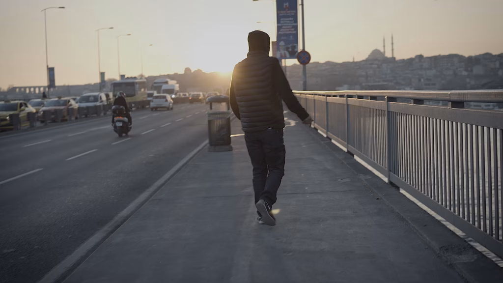 Kendal'a Bir Heykel (2026) filminde Kendal köprünün üzerinde tek başına yürüyor. Uzaktan çekimle Kendal'ın yalnızlığı kadrajda.