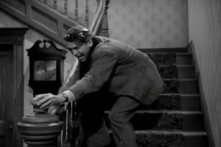 George Bailey, evindeki merdivenin gevşek trabzan topuzunu elinde tutuyor.