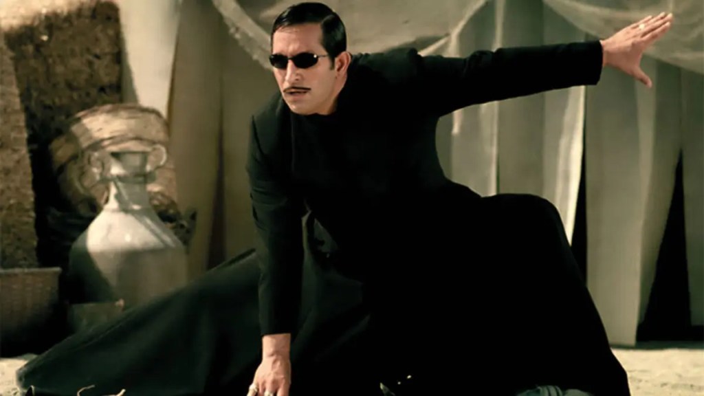 Gora filminden Matrix kıyafetli Arif karakteri dövüş hareketleri yapıyor.